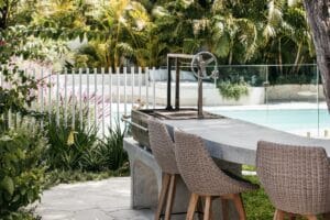 The curved polishedconcrete bench with bar stools and the elegant design of the smoker in the Collaroy Plateau Dream are set against the backdrop of the pool setting. Image: The Landscape Association